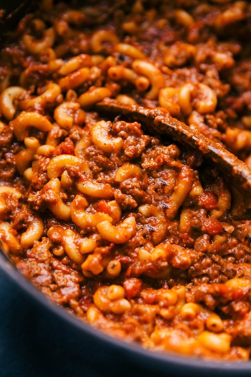 Freshly cooked goulash in a skillet with a wooden spoon, ready for serving.