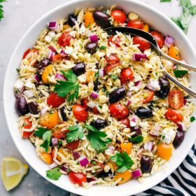 Delicious and healthy orzo pasta salad in a bowl with spoons, ready to be served.
