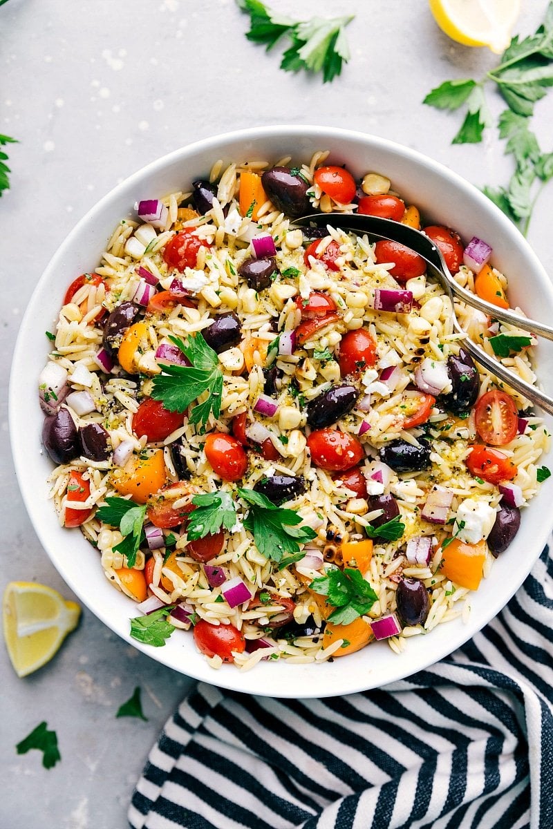 Overhead image of ready-to-eat Orzo Pasta Salad in a bowl with spoons in it.