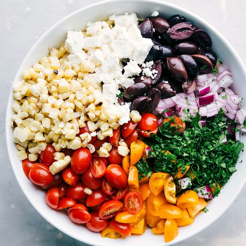 Process shot-- overhead image of all the salad ingredients in a bowl ready to be mixed for this orzo pasta salad