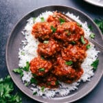 Porcupine meatballs served over a bed of rice, garnished with fresh herbs.