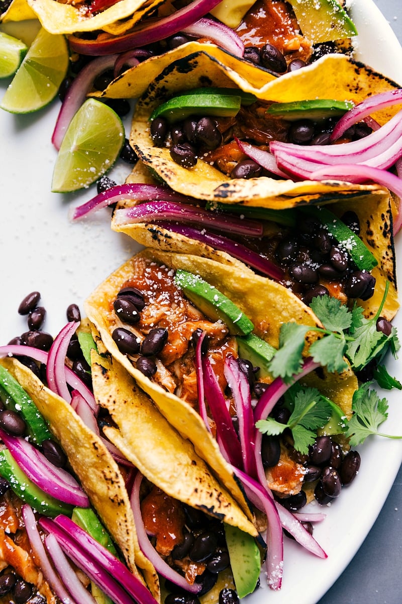 Finished chipotle chicken tacos, ready to eat, topped with fresh cilantro, pickled onions, and other toppings.