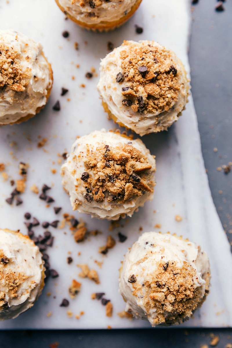 Overhead view of Chocolate Chip Cupcakes with cream cheese frosting and crumbled cookies .