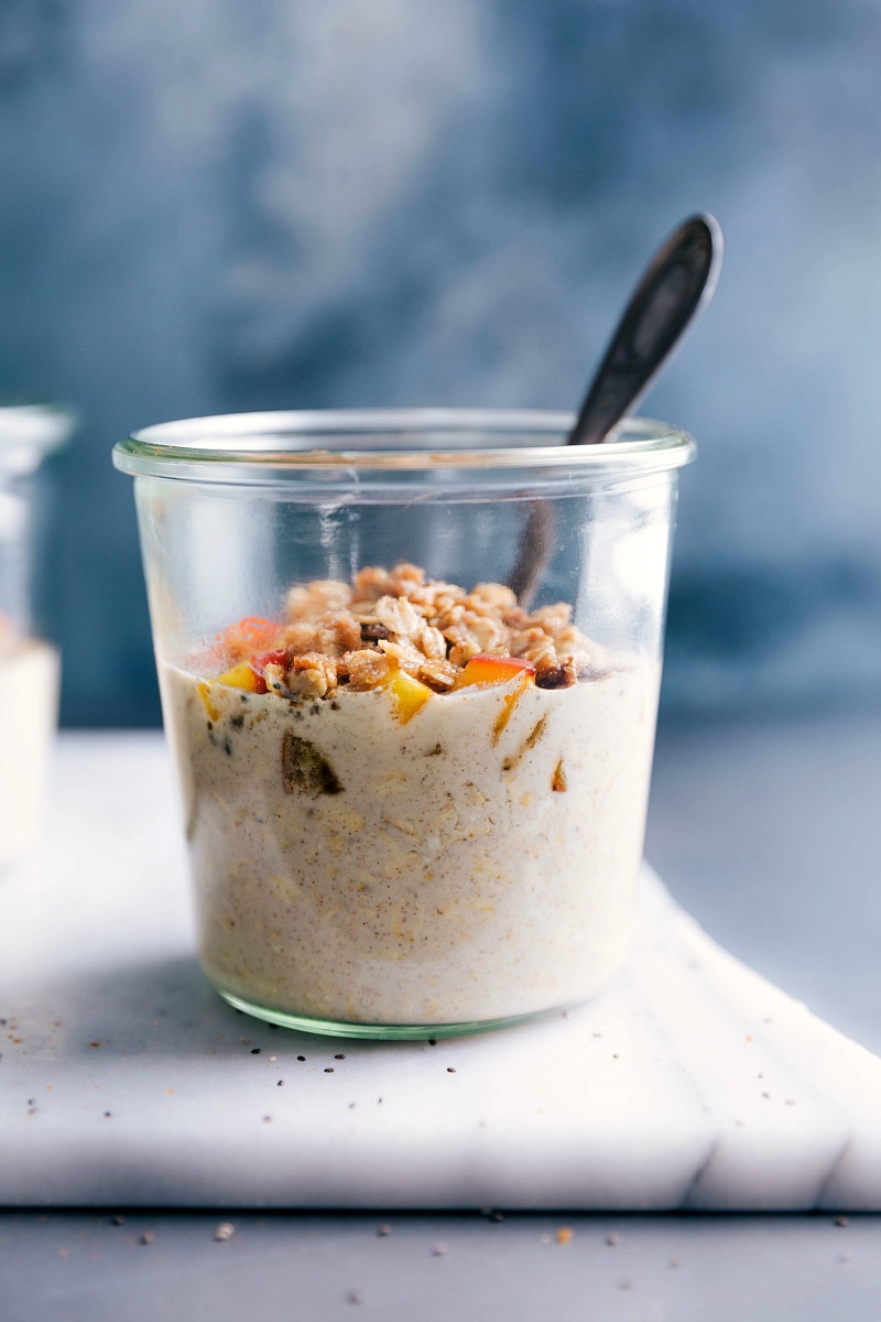 Peach overnight oats in a bowl, ready to be eaten, topped with fresh peach slices and crunchy granola.