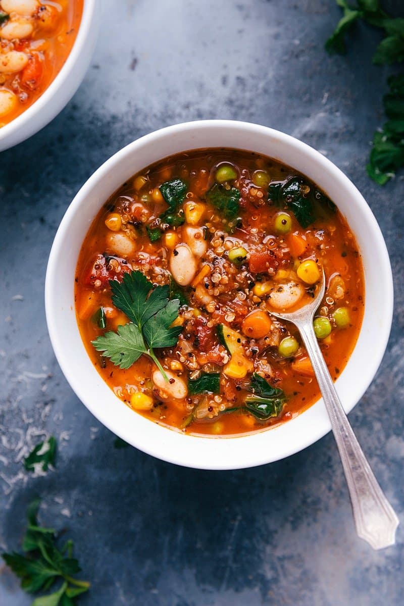 Healthy minestrone soup in a bowl with a spoon, featuring a variety of vegetables.