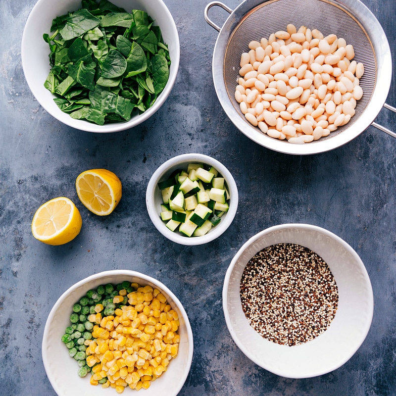 Components for the healthy minestrone soup recipe: individual bowls with prepped vegetables, beans, pasta, and herbs.