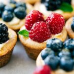 Mini fruit tarts topped with raspberries, blueberries, blackberries, and fresh mint.