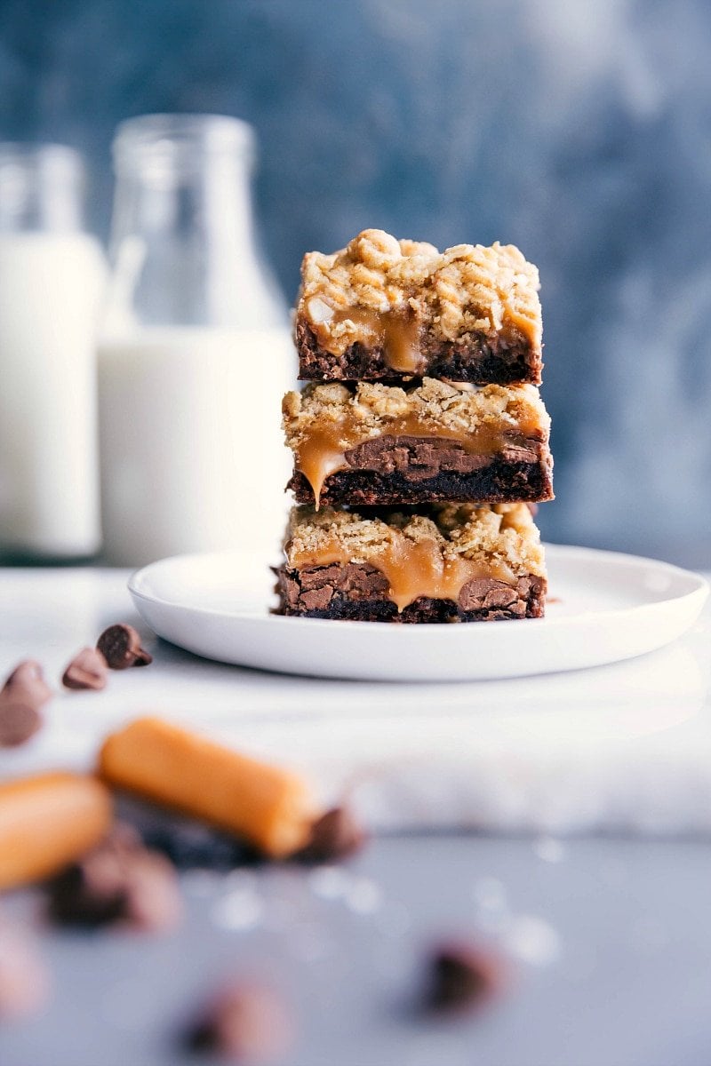 Brownie cookie bars stacked, with caramel oozing out from the center layers.