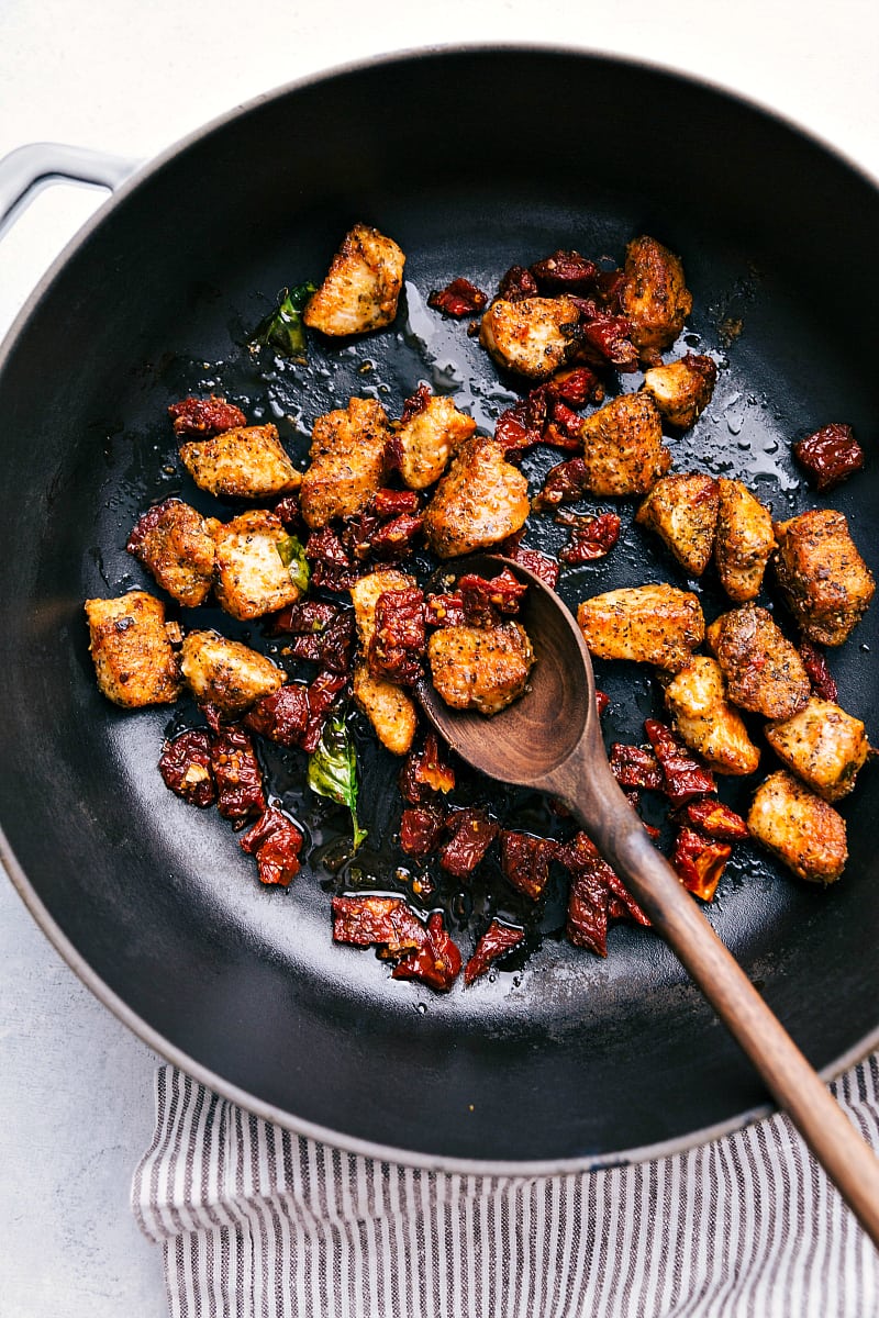 Process shot-- Overhead image of the chicken and sun-dried tomatoes being cooked in the pot.