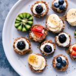 Healthy fruit tarts beautifully displayed on a tray, adorned with a variety of fresh fruit toppings.