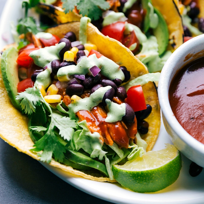 Close-up view of BBQ Chicken Tacos, with a bowl of barbecue sauce nearby.