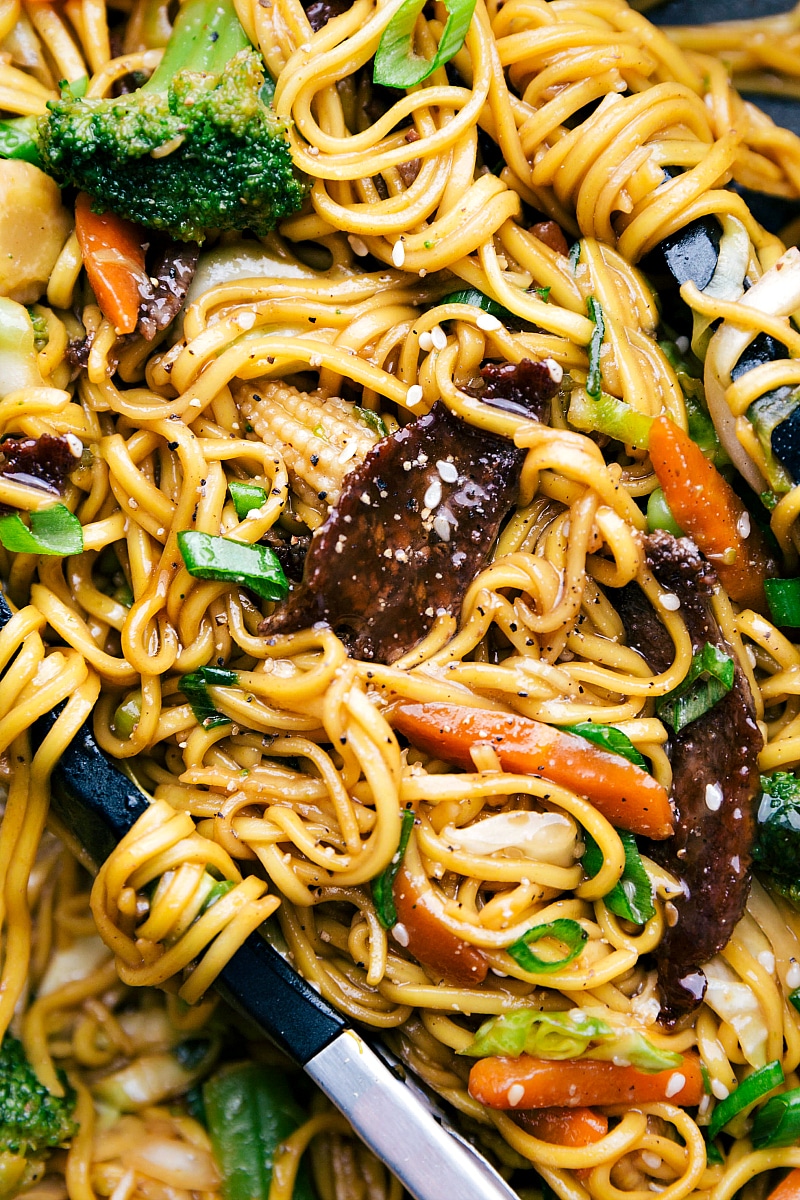 Up-close shot of finished Beef Chow Mein with tongs holding the noodles.