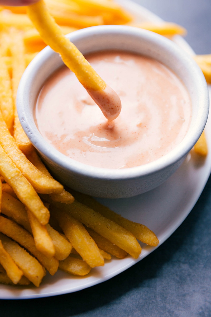 French fry being dipped into delicious condiment.