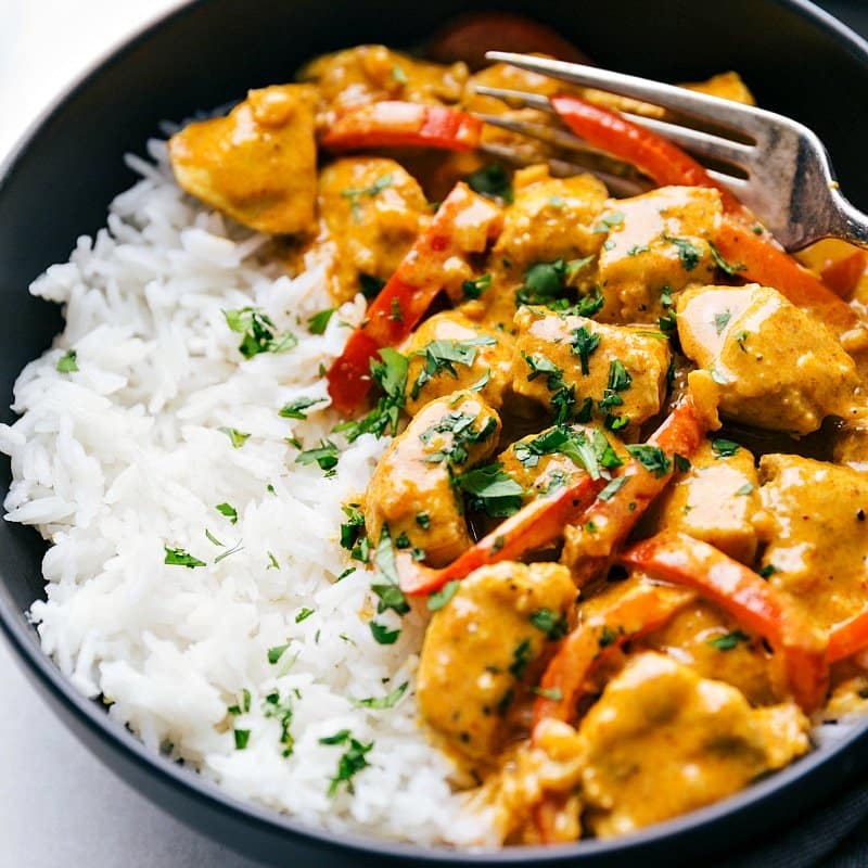 The finished chicken coconut curry on top of rice, garnished with fresh herbs, warm and ready to be enjoyed.
