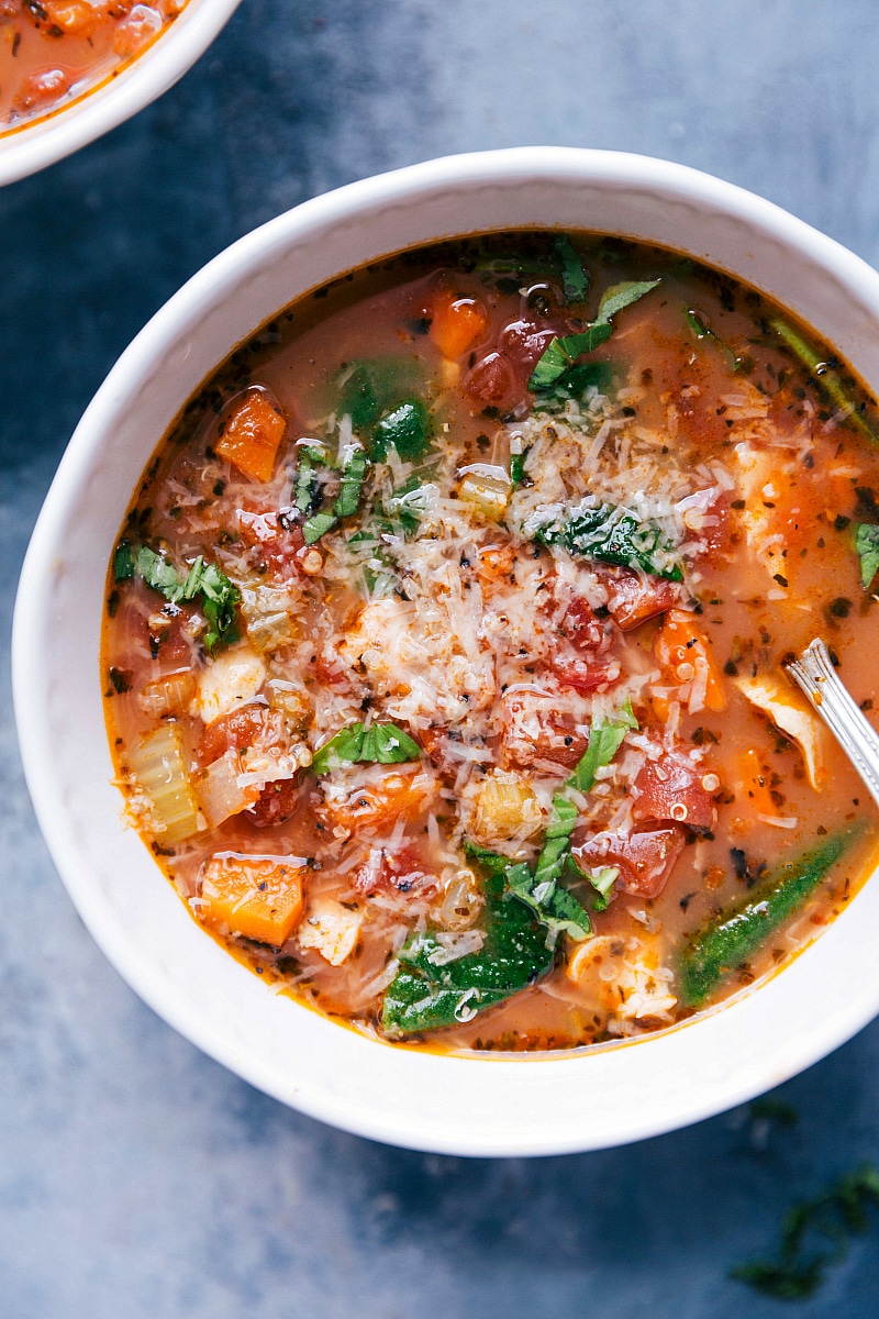 Overhead image of the Crock-pot Chicken Quinoa Soup in a bowl with fresh Parmesan melted over it.