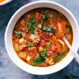 A bowl of hearty crockpot chicken quinoa soup, with chicken, quinoa, vegetables, and herbs.