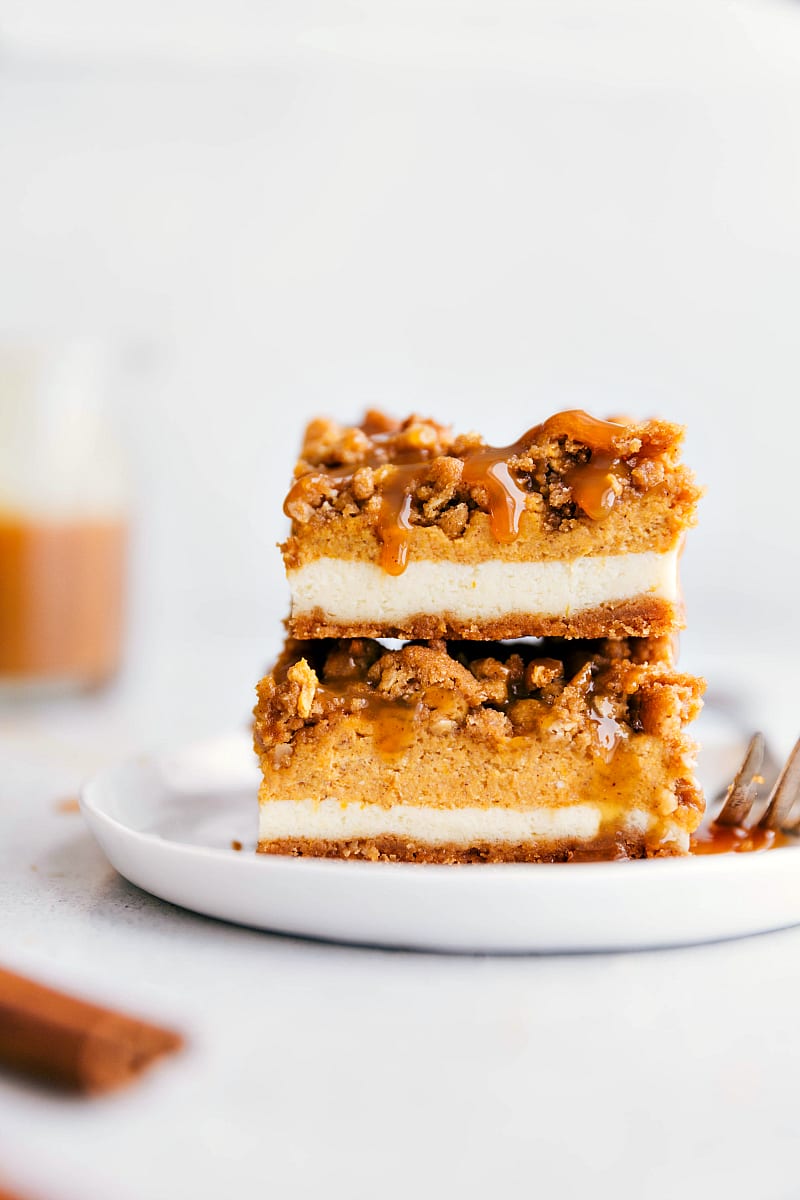 Up close shot of pumpkin cheesecake bars stacked on a white plate