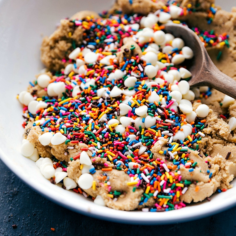 Process shot-- image of the sprinkles and white chocolate chips being added to the dough.