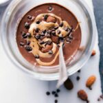 Chocolate almond overnight oats in a bowl, generously topped with almonds and chocolate chips.