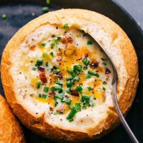 Savory baked potato soup topped with fresh herbs and melted cheese in a bread bowl, ready to be devoured.
