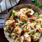 Simple and cheesy baked chicken alfredo served over a creamy pesto pasta topped with bacon and pine nuts!