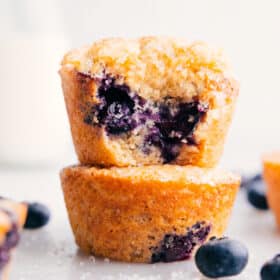 Healthy blueberry muffins stacked on top of each other with a bite out of the top one.