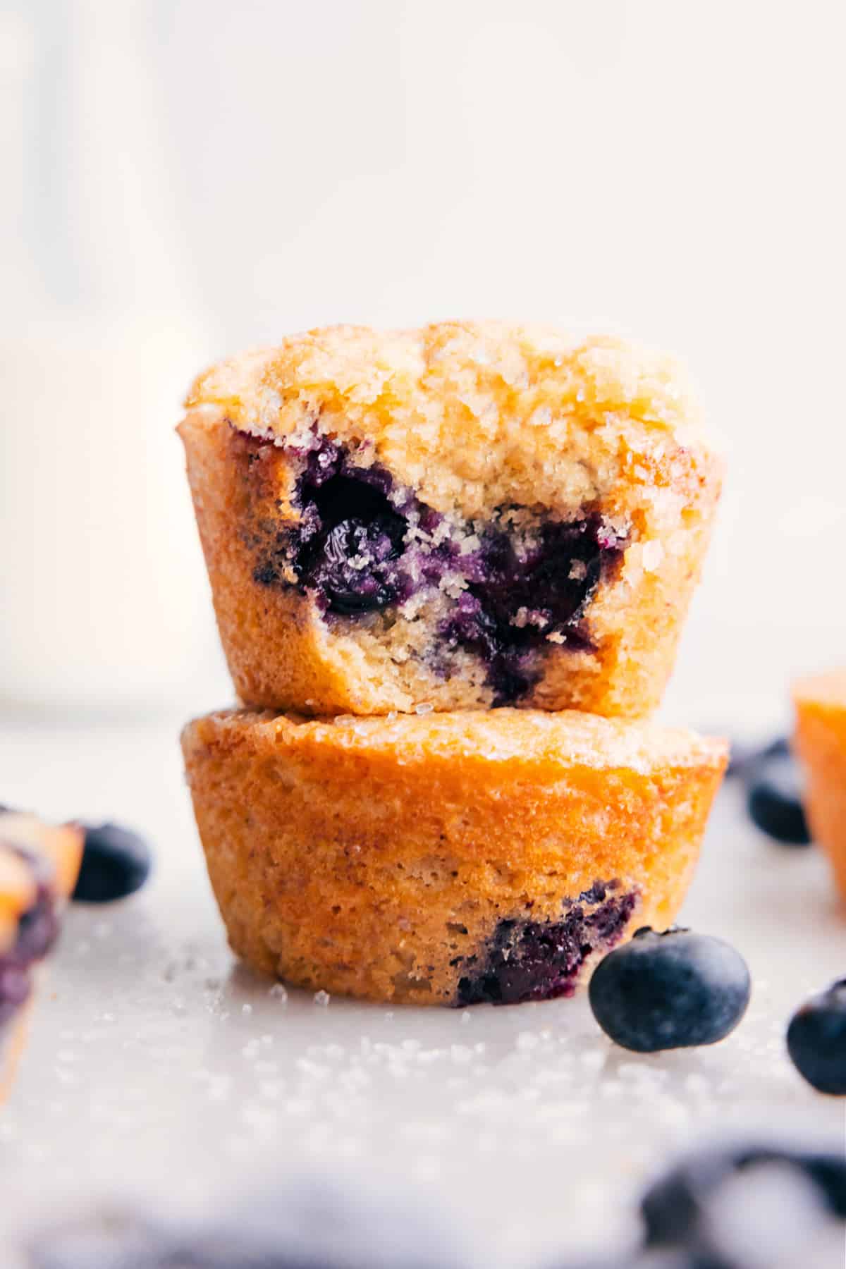 Healthy blueberry muffins stacked on top of each other with a bite out of the top one.