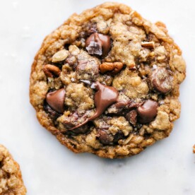 Freshly baked and delicious oatmeal pecan cookie with melted chocolate chips on top, a sprinkle of fresh sea salt, and baked pecans.