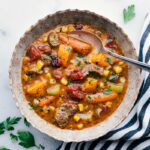 A bowl filled with hearty and delicious sweet potato stew, brimming with flavor and vegetables, accompanied by a spoon, inviting you to savor its wholesome goodness.