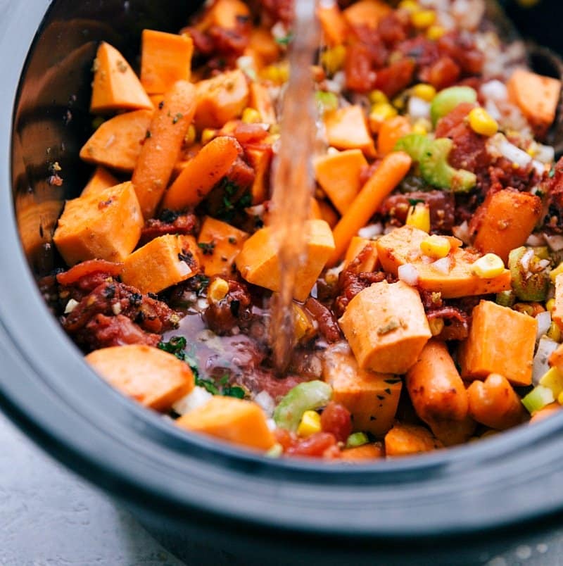 Water being poured into the slow cooker, combining with the other ingredients to create a flavorful base. 