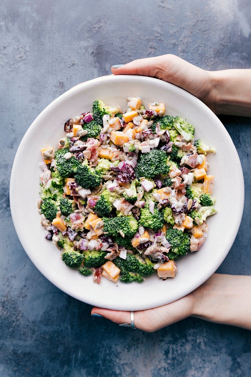 Overhead image of Broccoli Salad in a bowl with hands holding the bowl.