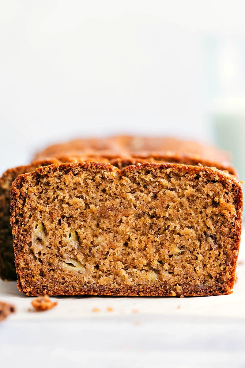 Up-close shot of a slice of this healthy banana bread with the rest of the loaf in the background.