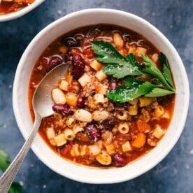 Pasta e fagioli in a bowl with a spoon and garnished with fresh parsley.