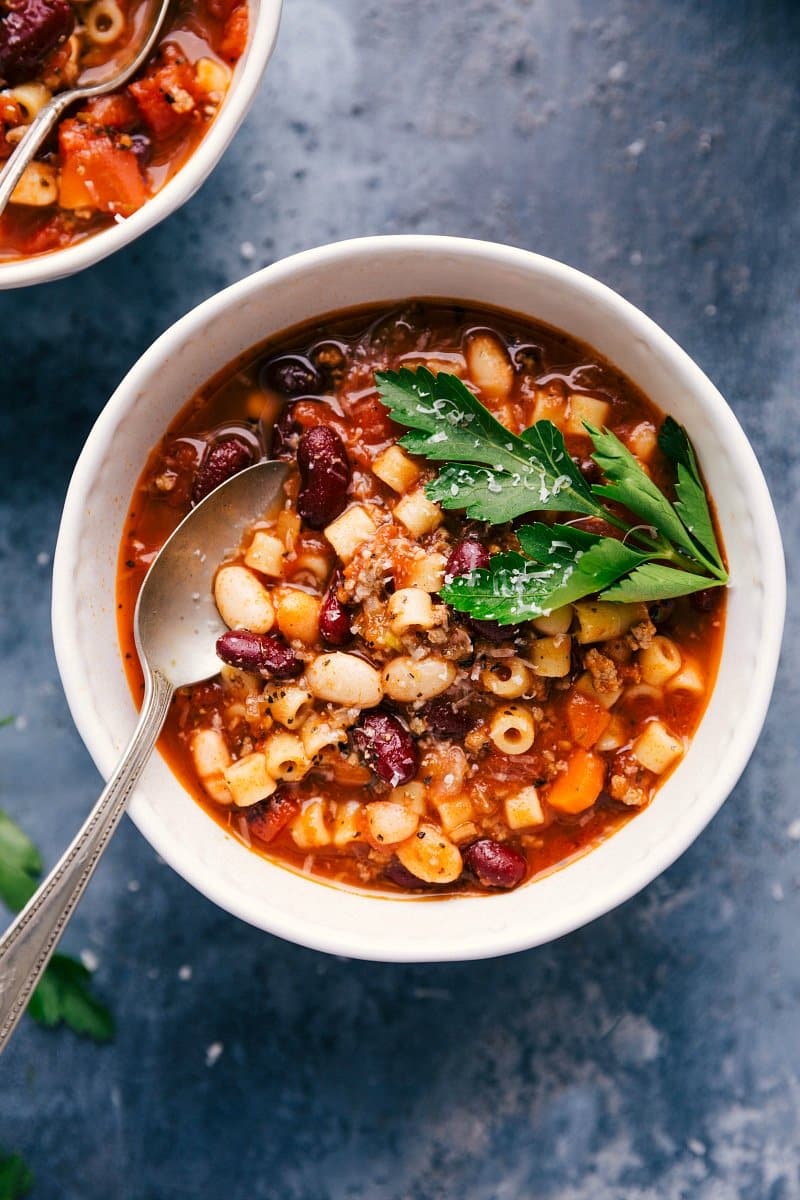 Overhead image of Pasta e Fagioli in a bowl with a spoon in it and fresh parsley.