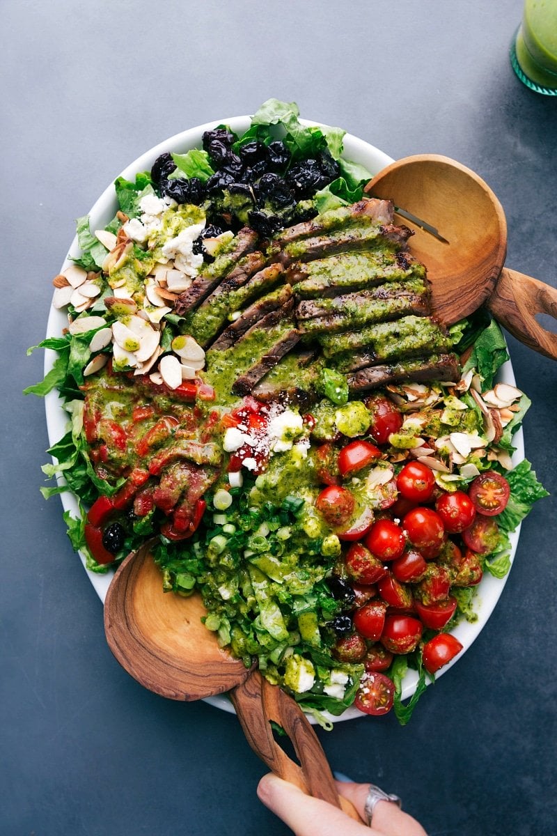 Steak salad with an assortment of fresh vegetables, dressed and ready to be tossed.