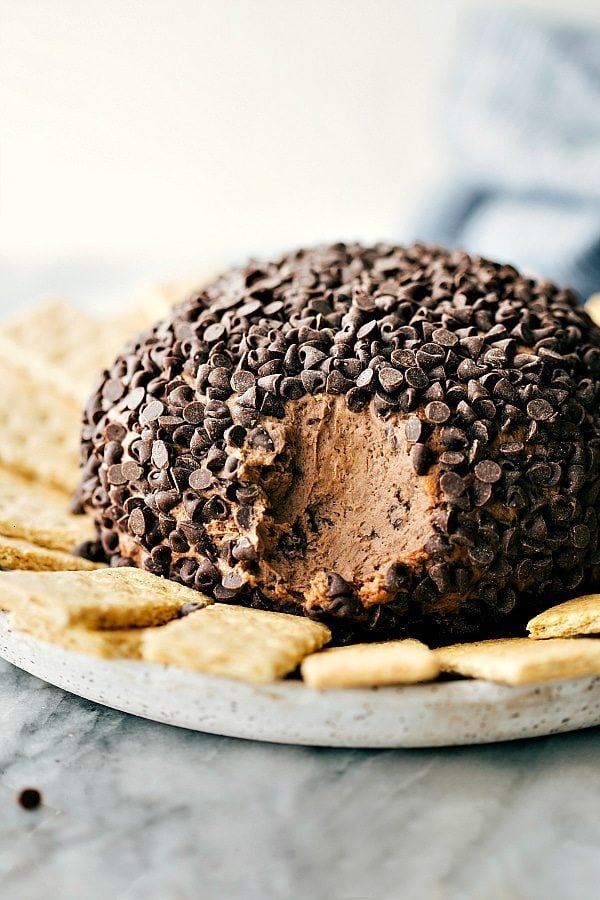 Simple and delicious brownie 'batter' dessert cheese ball covered in chocolate chips with graham crackers surrounding it.