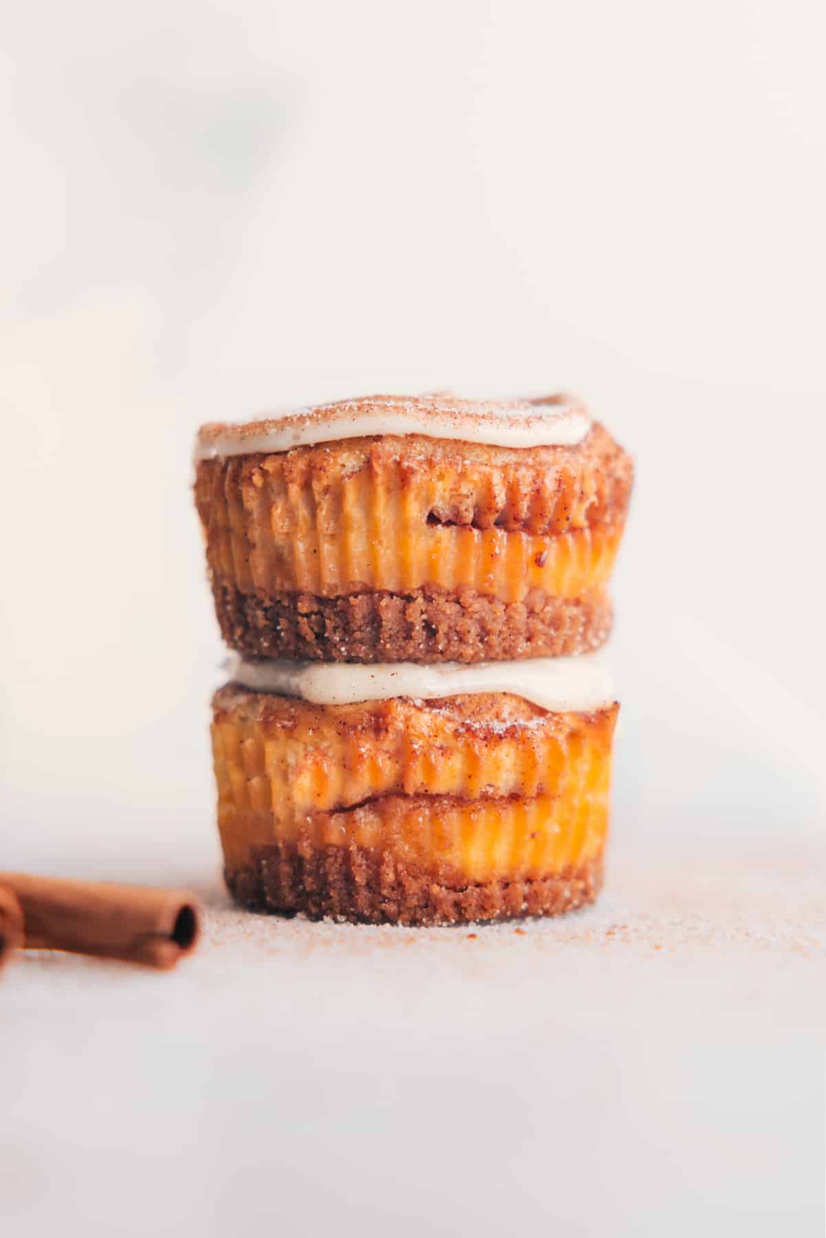 Cinnamon Roll Cheesecakes Recipe Cinnamon Roll Cheesecakes stacked together, topped with frosting.