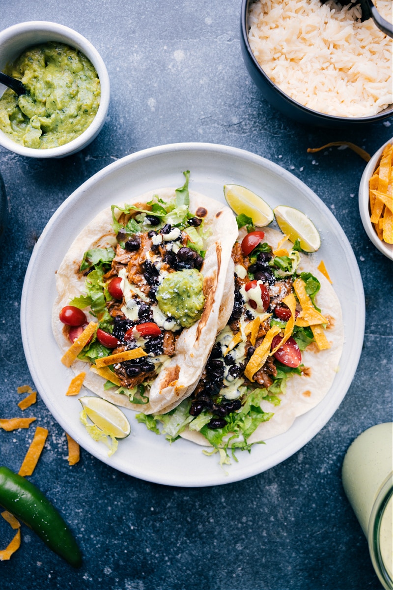 This Cafe Rio Sweet Pork Recipe is a restaurant copycat recipe that is even better homemade (not to mention cheaper!) This succulent slow-cooked pork is perfectly sweet with a touch of spice and delicious served in tacos, burritos, or a big salad! Recipe via ChelseasMessyApron #dinner #quick #easy #simple #copcatrecipe #familyfriendly #kidfriendly #caferio #sweetpork #recipe Overhead image of the Cafe Rio Sweet Pork recipe on a plate