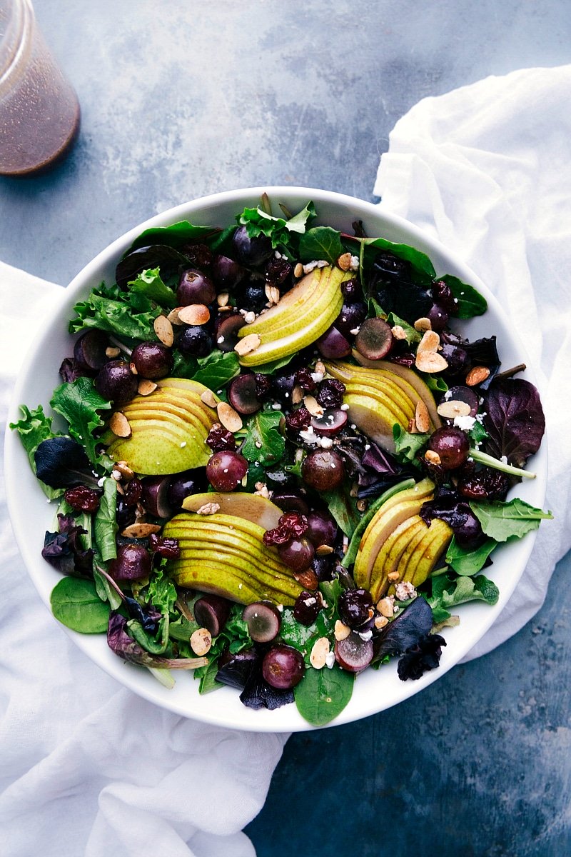 Vibrant pear, grape, and cherry green salad with cherry balsamic dressing on the side, a refreshing delight.