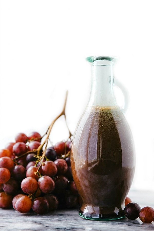 Image of Cherry Balsamic Salad Dressing in the container with fresh grapes on the side.