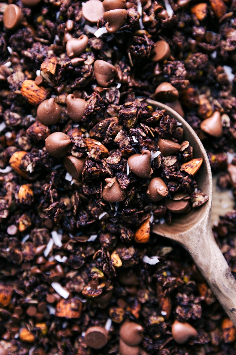 A close-up image of finished Chocolate Granola, scooped with a wooden spoon.