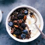 Bowl of chocolate granola, beautifully presented with fresh berries and yogurt.