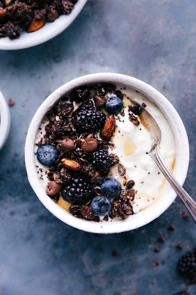 Bowl of chocolate granola, beautifully presented with fresh berries and yogurt.