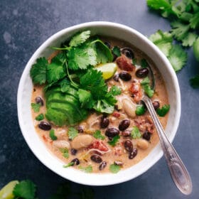 Warm bowl of green chile chicken enchilada soup topped with fresh herbs and avocado slices, ready to enjoy.