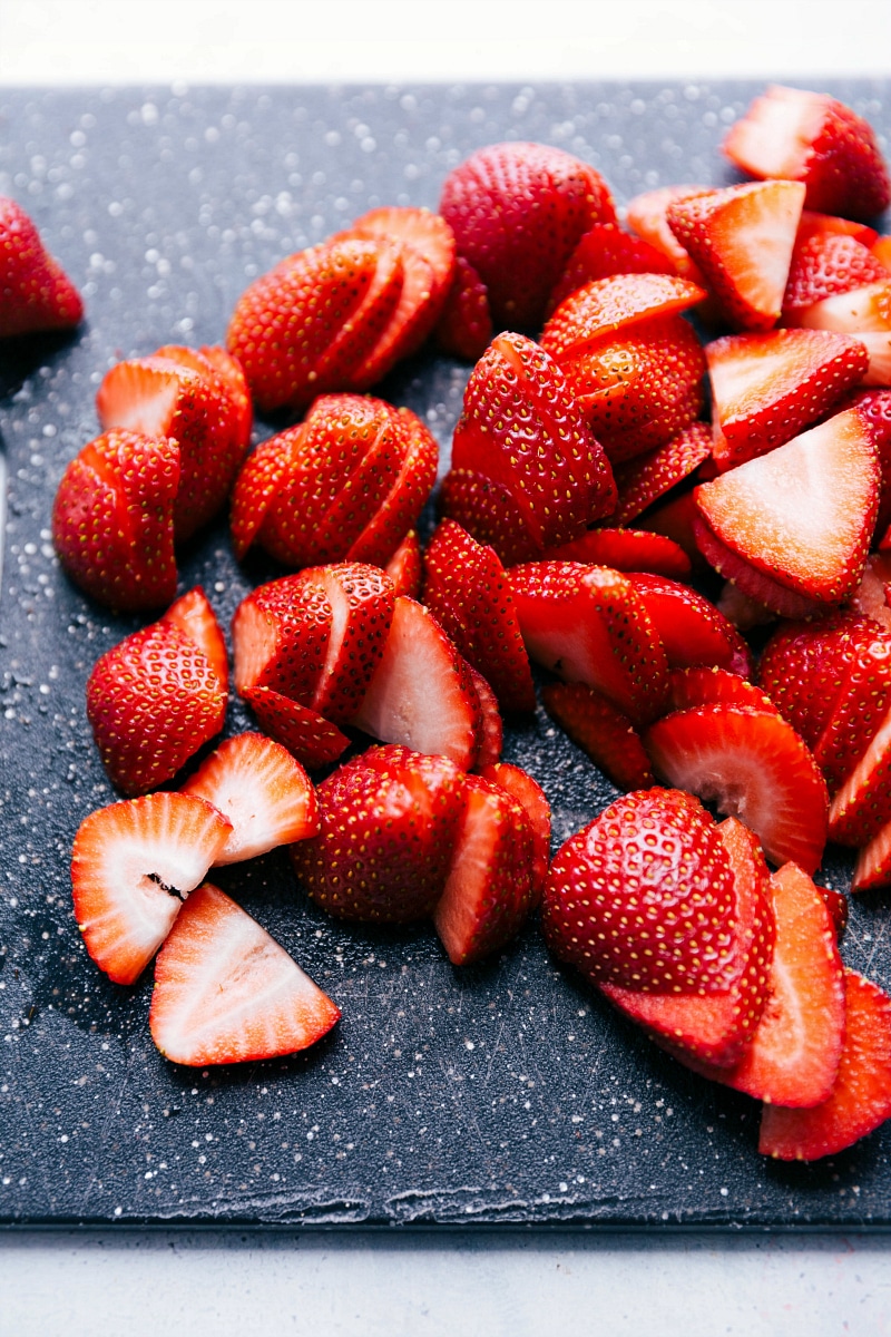 View of sliced strawberries on a cutting board.