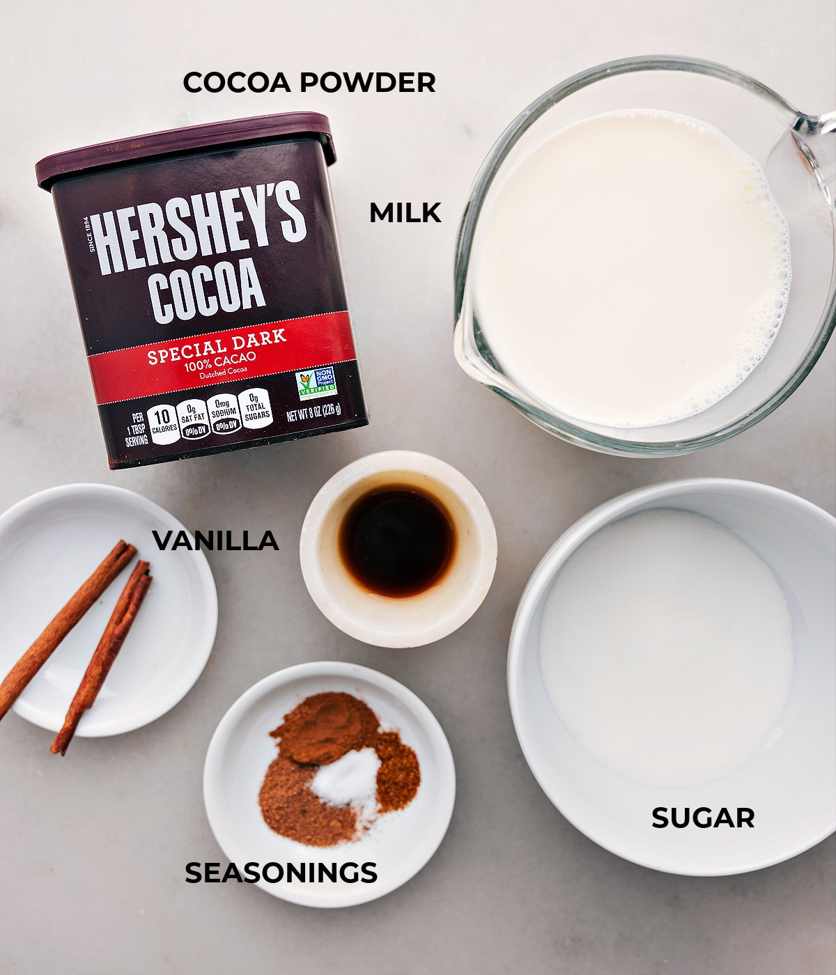 Arrangement of ingredients including milk, rich cocoa powder, and additional elements for the Mexican Hot Chocolate recipe.