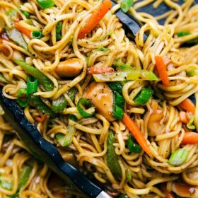 Prepared Chicken chow Mein with tongs in the skillet.