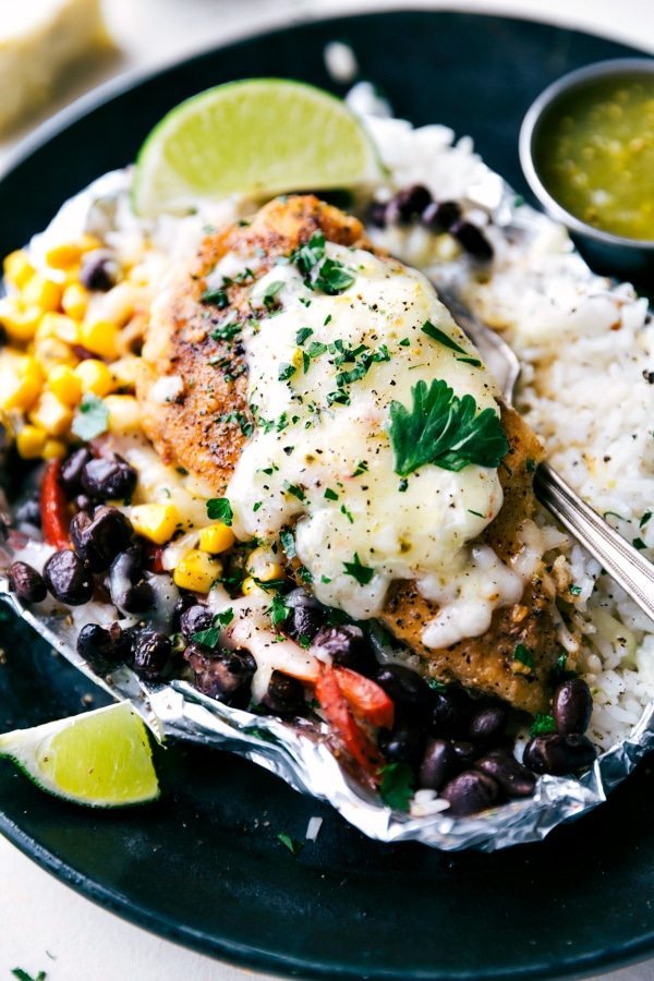 Creamy salsa verde chicken with rice and veggies all cooked at once in a foil packet! No need to pre-cook the rice or chicken. This dish takes no more than 10 minutes to assemble and is bursting with delicious Mexican flavor. Recipe via chelseasmessyapron.com