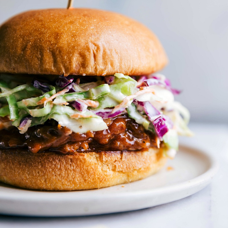 Finished BBQ pulled pork in crockpot served on a bun atop coleslaw, creating a delicious sandwich.