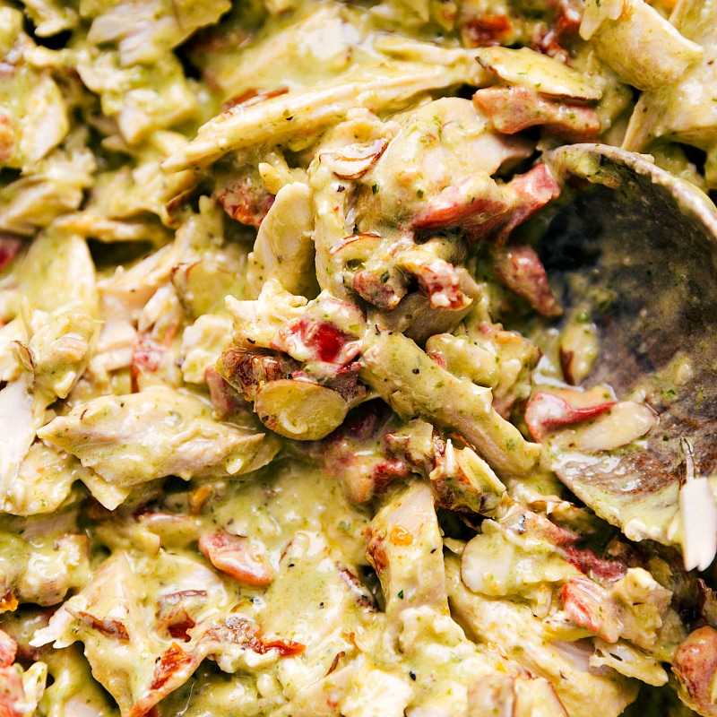 Chicken mixture generously coated with delicious dressing, a key step in preparing salad with pesto chicken.